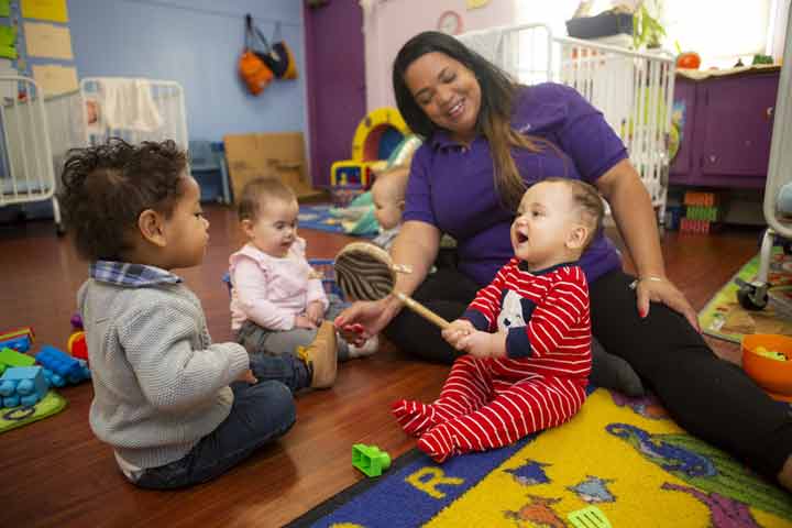 Teacher with infant and toddler engaged in play.