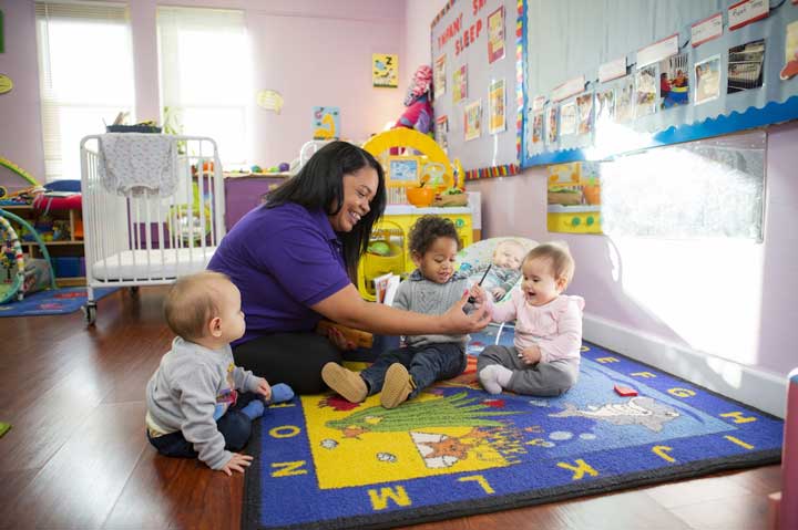 Teacher and group of toddlers sitting on a mat together